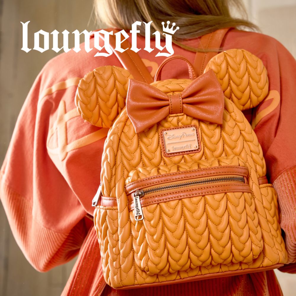 Young woman wearing a clear Mickey-shaped Loungefly backpack with a teal Mickey head pattern.