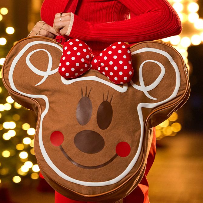 Woman in red sweater holding Minnie Mouse Gingerbread Big Face Tote.