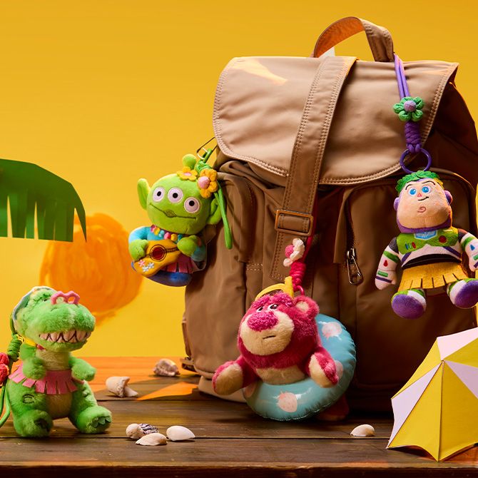 Rex, Lotso, Alien, and Buzz Plush keychains attached to a brown backpack on a yellow background.