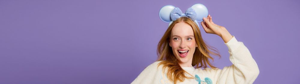 Woman Wearing sparkly Minnie ears with Disneyland 70th anniversary balloons in the background.