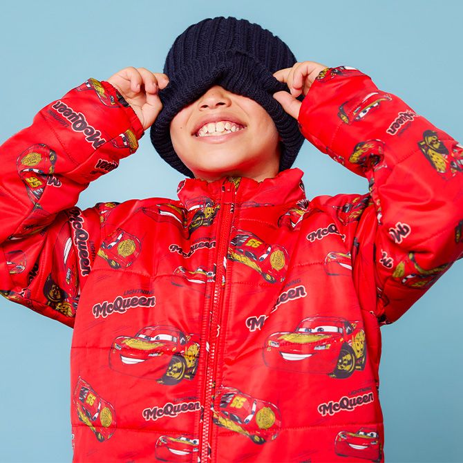 A boy standing outside in a Lightning McQueen Spirit Jersey.