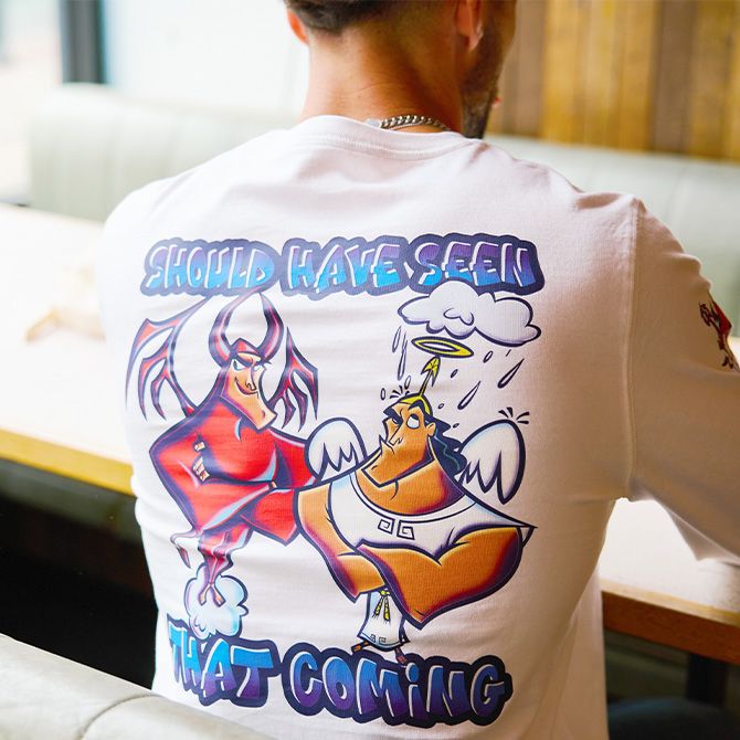 Young man on a boat holding a rope & wearing a gray t-shirt with a progression of all the different Donald Duck designs and text that reads &ldquo;Donald Through The Years&rdquo;.