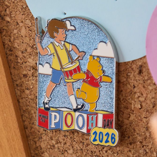 Winnie the Pooh and Christopher Robin pin featuring Pooh Day 2026 text, attached to a corkboard with colored paper circles.