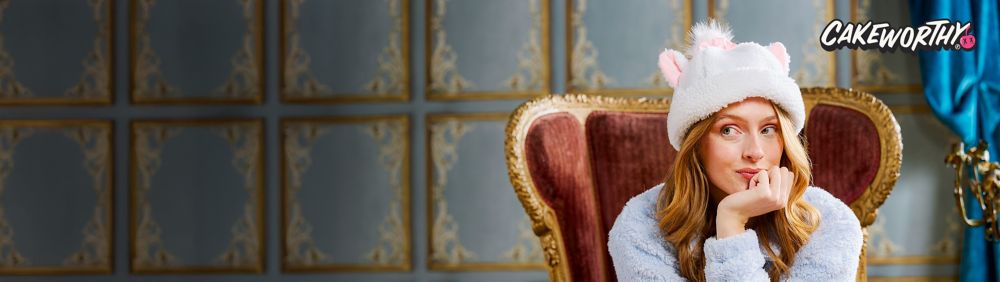 Young woman outside wearing a pink Daisy Duck sweater in honor of Daisy Duck's 85th birthday. Text: Cakeworthy.