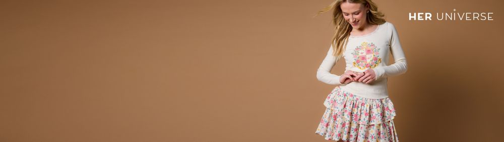 Two people wear red plaid shirts with Minnie Mouse holiday embroidery. Gift boxes and a decorated Christmas tree are in the background.