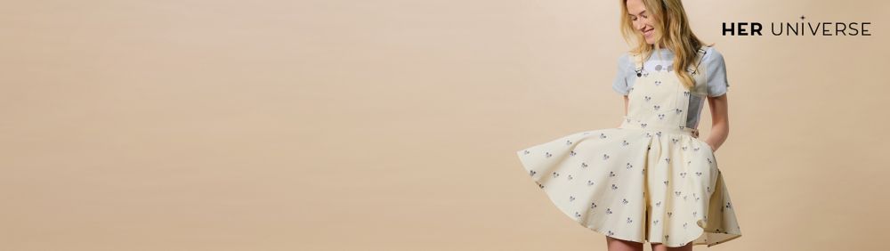 Two people wear red plaid shirts with Minnie Mouse holiday embroidery. Gift boxes and a decorated Christmas tree are in the background.