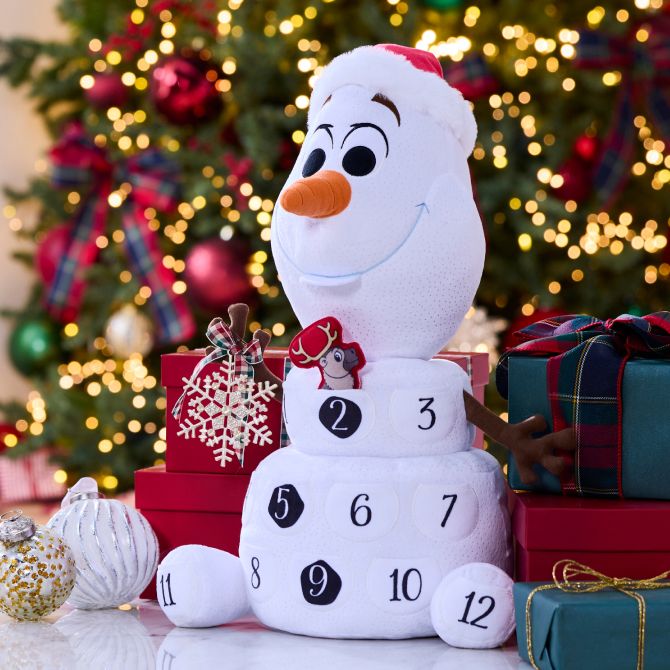 Olaf plush from Frozen, wearing a Santa hat, is decorated as a countdown calendar, surrounded by wrapped gifts, ornaments, and a brightly lit Christmas tree.