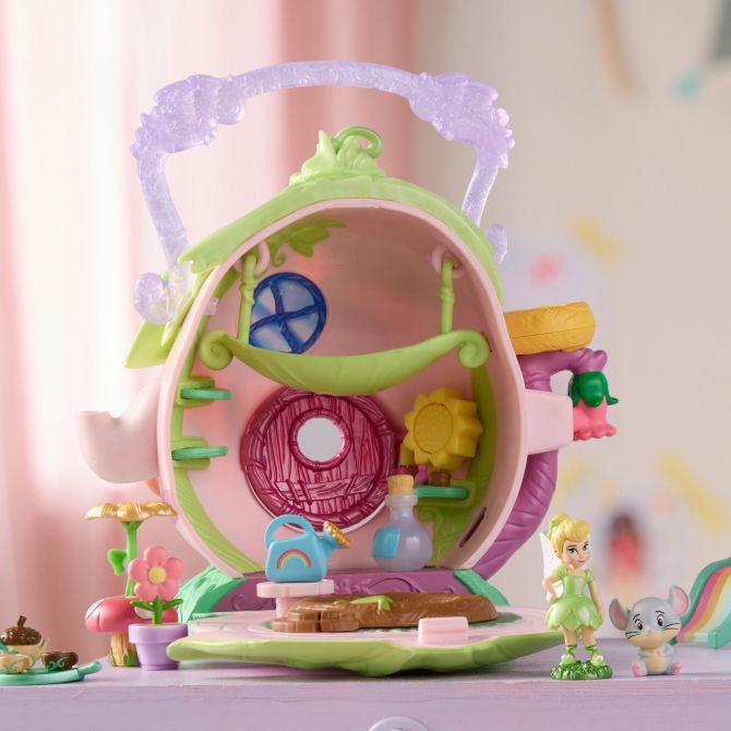 Tinker Bell playset shaped like a teapot is open to reveal tiny accessories and a Tinker Bell figure, set on a pastel dresser with pink curtains.
