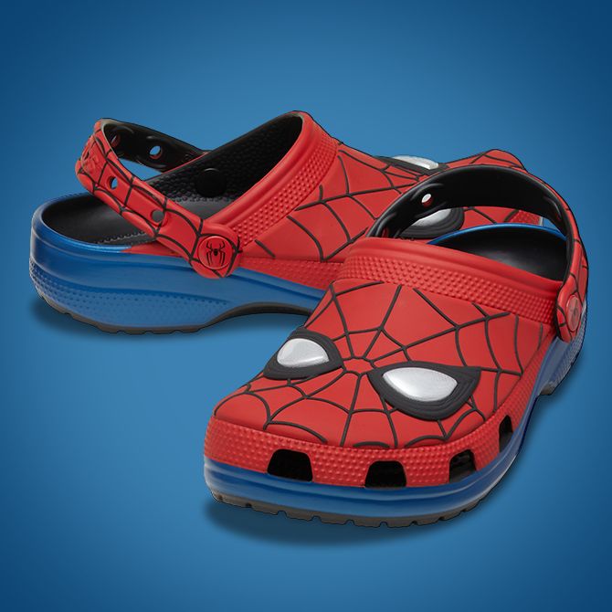 Red Spider-Man-themed Crocs with web and mask design, shown against a plain blue gradient background.