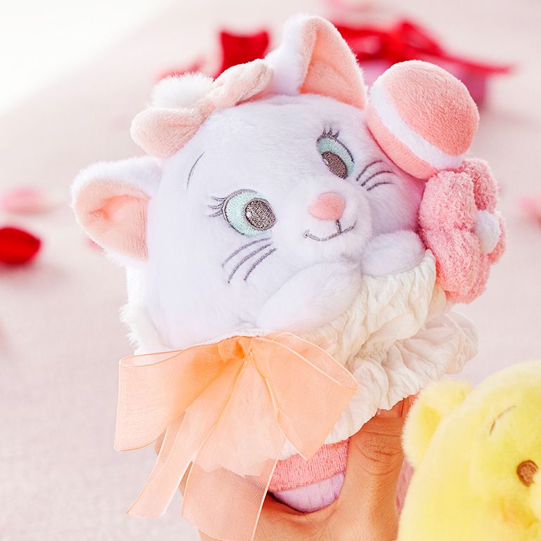 A person holding a plush version of Marie from the Aristocats shaped as a bouquet of flowers.